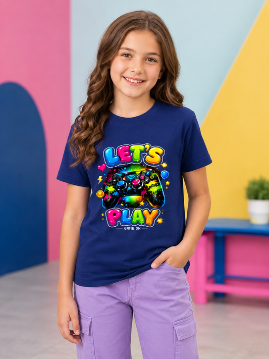 Girl wearing a blue video game controller t-shirt with colorful text and graphics in a bright room.