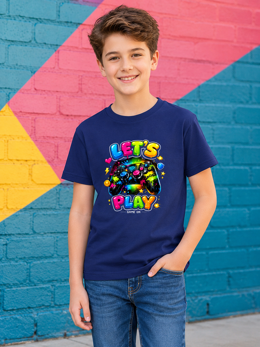 Boy wearing a blue video game controller t-shirt with colorful text and graphics against a multicolored brick wall.